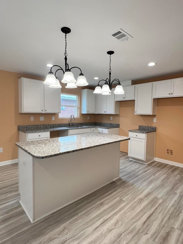 kitchen featuring light hardwood / wood-style floors, white cabinetry, pendant lighting, and a center island