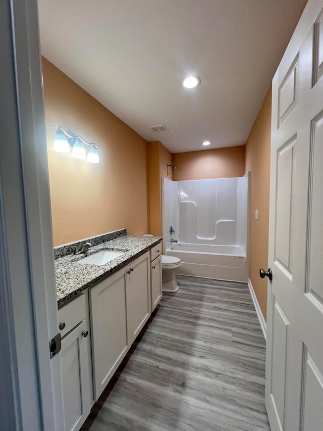 full bathroom featuring hardwood / wood-style floors, tub / shower combination, vanity, and toilet