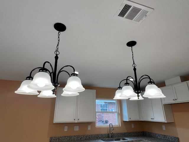 room details with white cabinets, a chandelier, sink, and hanging light fixtures