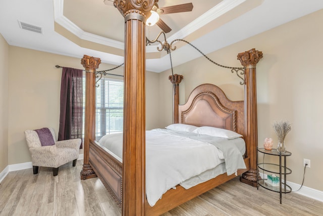 bedroom featuring ornamental molding, light hardwood / wood-style floors, ceiling fan, and a raised ceiling