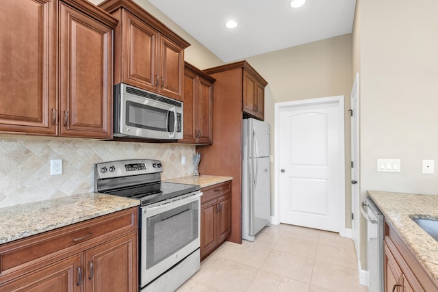 kitchen with stainless steel appliances, tasteful backsplash, and light stone counters