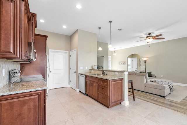 kitchen featuring stainless steel appliances, sink, light stone counters, ceiling fan, and hanging light fixtures