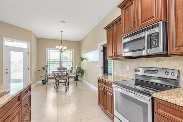 kitchen with tasteful backsplash, an inviting chandelier, light stone counters, and stainless steel appliances