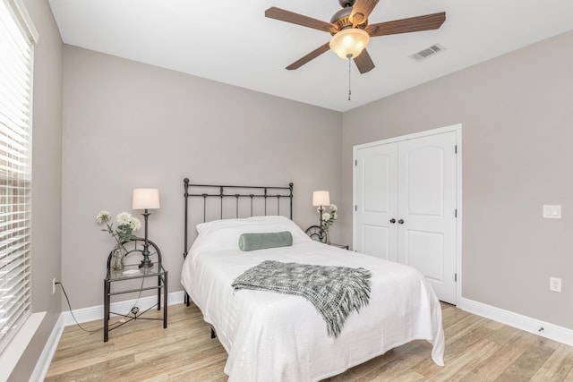 bedroom with light hardwood / wood-style flooring, ceiling fan, and a closet