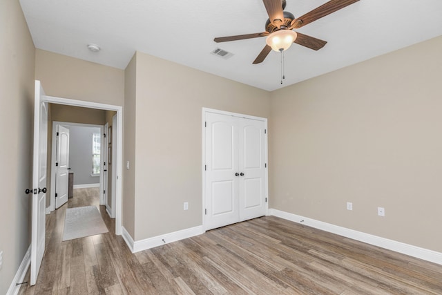 unfurnished bedroom with wood-type flooring, ceiling fan, and a closet