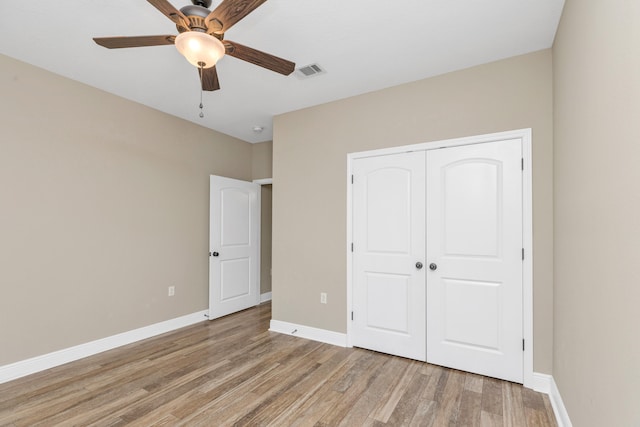 unfurnished bedroom featuring ceiling fan, a closet, and light wood-type flooring