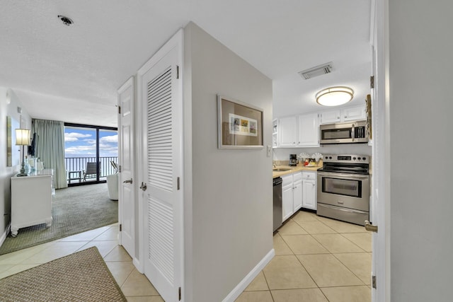 4100 E Co Hwy Unit 30A 1102 # 1102, Santa Rosa Beach, FL 32459 - kitchen featuring appliances with stainless steel finishes, light tile patterned flooring, floor to ceiling windows, white cabinets, and light countertops