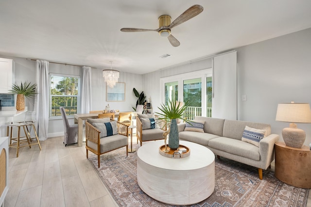 living room with ceiling fan with notable chandelier and light wood-type flooring