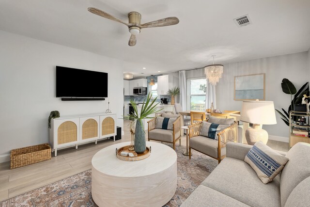 living room featuring light wood-type flooring and ceiling fan with notable chandelier