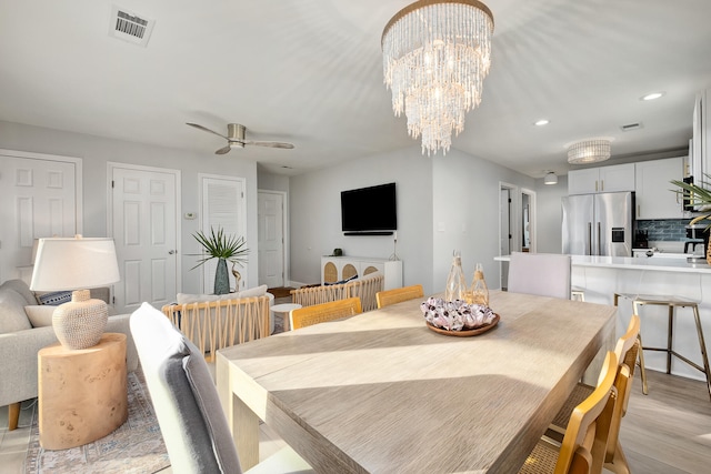 dining area with light wood-type flooring and ceiling fan with notable chandelier