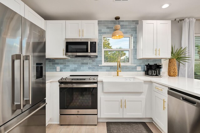 kitchen featuring stainless steel appliances, sink, hanging light fixtures, white cabinets, and decorative backsplash