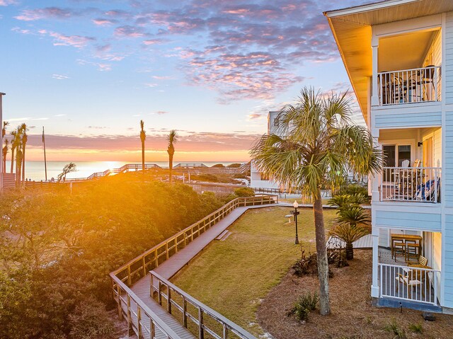 yard at dusk featuring a water view and a balcony