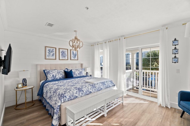 bedroom with access to outside, wood-type flooring, ornamental molding, a textured ceiling, and a notable chandelier