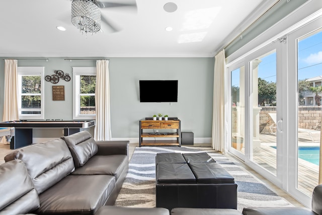 living room featuring light wood-type flooring, a wealth of natural light, ceiling fan, and crown molding