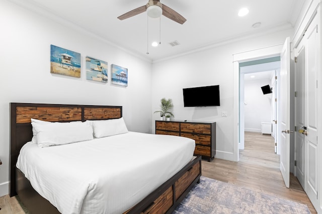 bedroom with ornamental molding, light hardwood / wood-style flooring, ceiling fan, and a closet