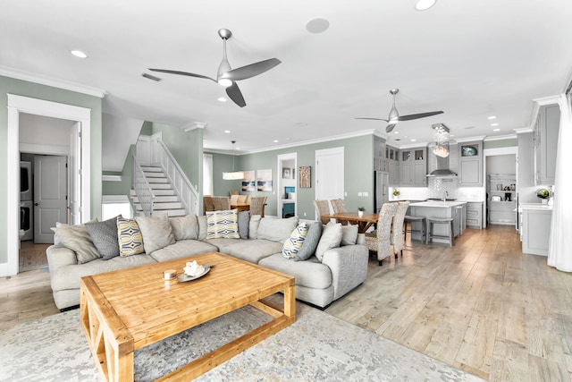 living room featuring ceiling fan, sink, light hardwood / wood-style flooring, and crown molding