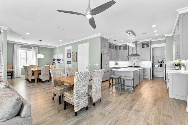 dining space with ceiling fan, sink, light wood-type flooring, and crown molding