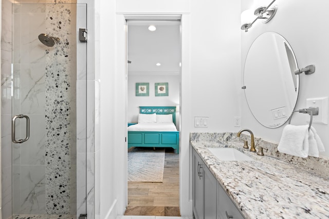 bathroom featuring vanity, hardwood / wood-style floors, ornamental molding, and a shower with shower door