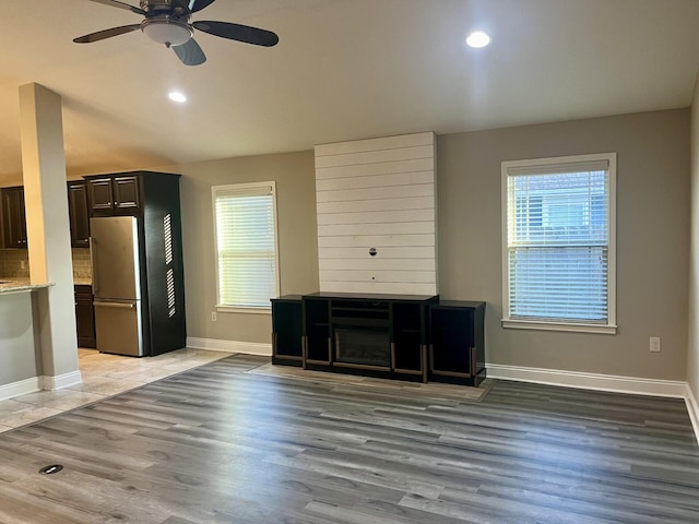 unfurnished living room featuring ceiling fan, a large fireplace, and light hardwood / wood-style floors