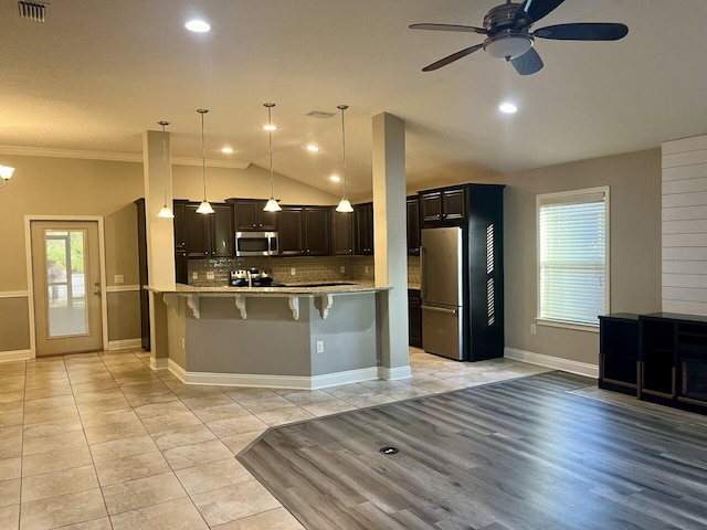 kitchen with ceiling fan, stainless steel appliances, pendant lighting, a breakfast bar, and ornamental molding