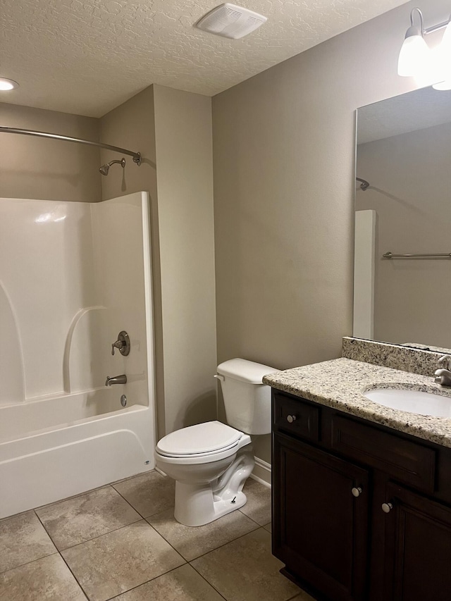 full bathroom featuring vanity, tile patterned floors, washtub / shower combination, toilet, and a textured ceiling