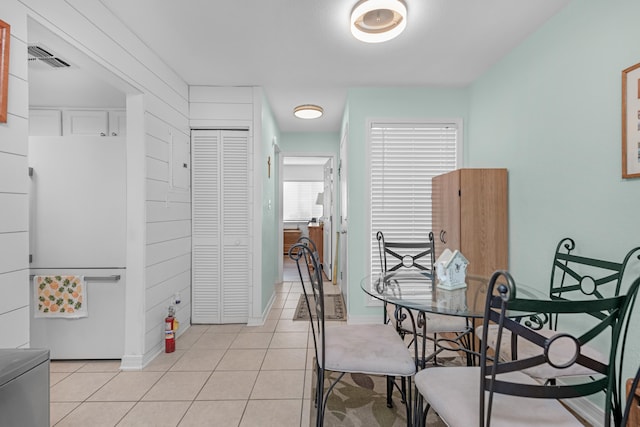 dining area with wooden walls and light tile patterned floors