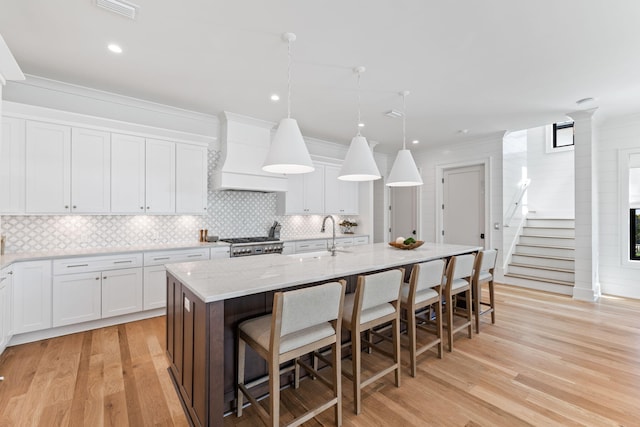 kitchen with pendant lighting, a kitchen breakfast bar, a center island with sink, and white cabinets