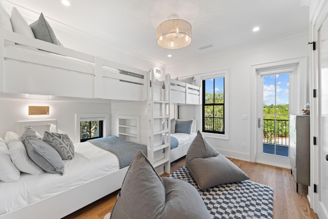 bedroom featuring access to exterior, light hardwood / wood-style floors, multiple windows, and crown molding