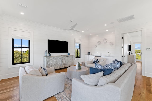 living room featuring a wealth of natural light, ceiling fan, and light wood-type flooring