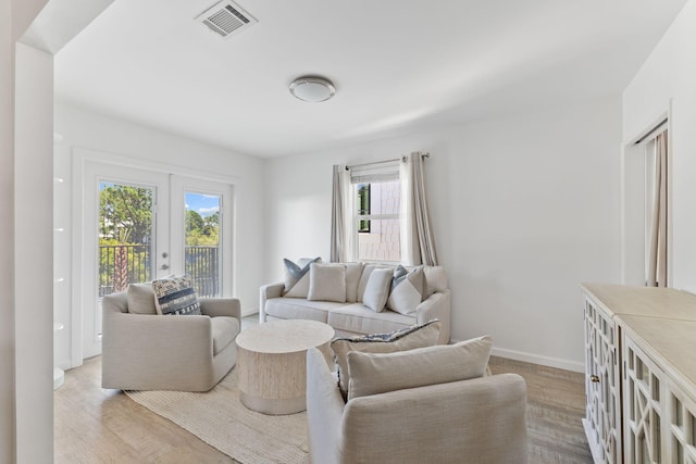 living room featuring french doors, a wealth of natural light, and light hardwood / wood-style floors