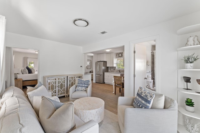 living room with a wealth of natural light, sink, and light hardwood / wood-style floors