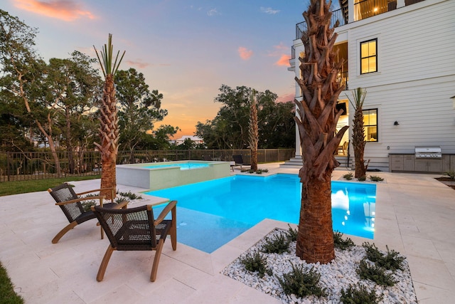 pool at dusk with a grill and a patio area