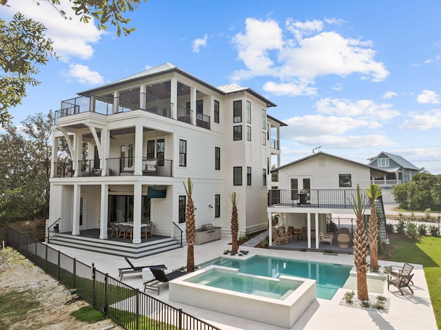 rear view of property featuring a balcony, a patio, and an in ground hot tub