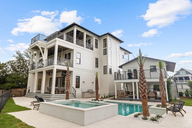 rear view of property with a swimming pool with hot tub, a patio, and a balcony