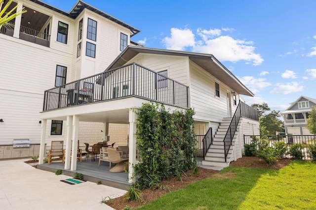 rear view of property with a balcony, a yard, and a patio area