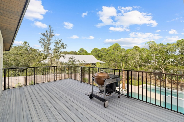 wooden terrace with area for grilling and a fenced in pool