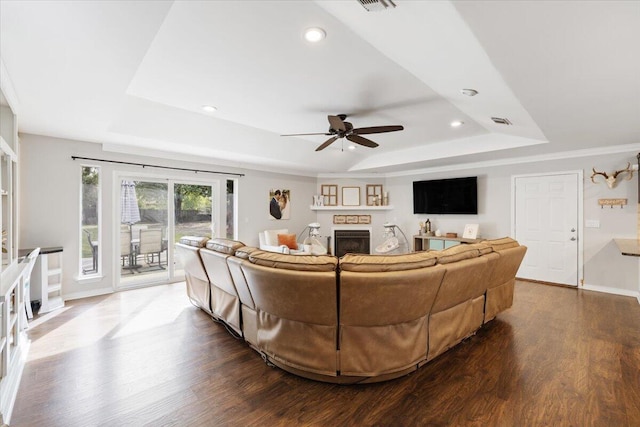 living room featuring wood-type flooring, ceiling fan, and a tray ceiling