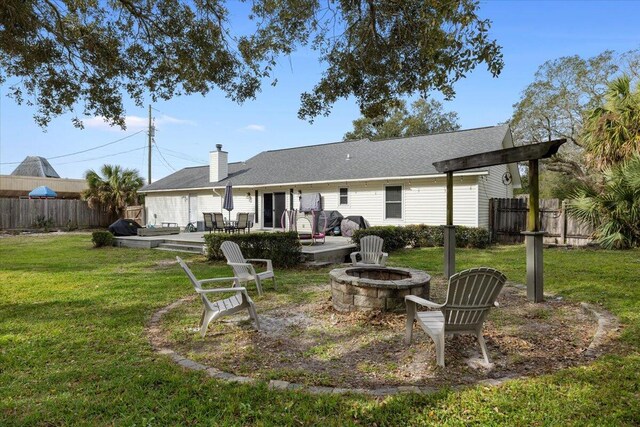 rear view of property featuring a patio area, a yard, a deck, and a fire pit