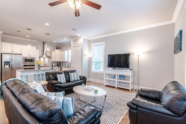 living room with ceiling fan, light hardwood / wood-style floors, and ornamental molding