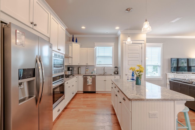 133 Grande Pointe Cir, Inlet Beach, FL 32461 - kitchen with appliances with stainless steel finishes, ornamental molding, light wood-style flooring, a center island, and white cabinetry