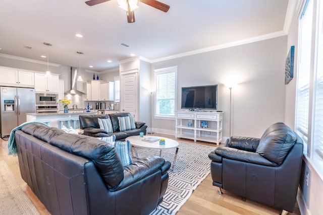 living room with light hardwood / wood-style floors, ceiling fan, and ornamental molding