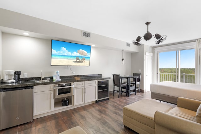 interior space with white cabinetry, appliances with stainless steel finishes, decorative light fixtures, beverage cooler, and dark hardwood / wood-style flooring