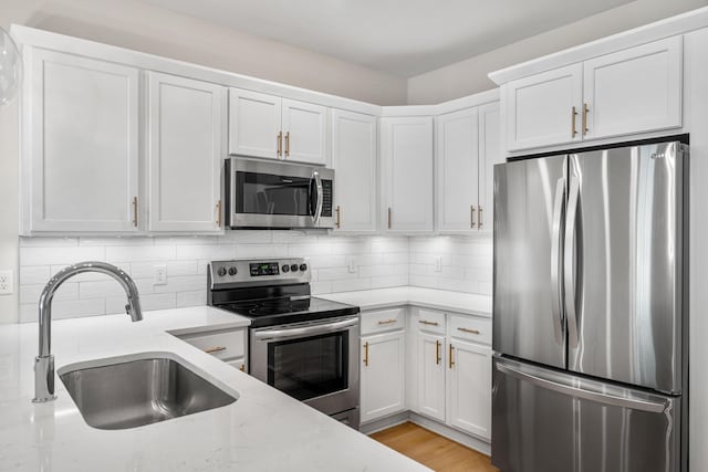 kitchen with white cabinetry, light stone countertops, sink, and appliances with stainless steel finishes