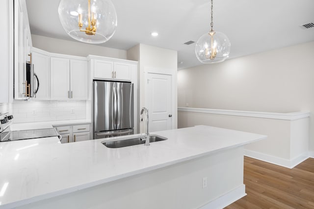 kitchen featuring kitchen peninsula, stainless steel appliances, sink, decorative light fixtures, and white cabinetry