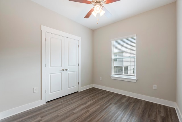 unfurnished bedroom with ceiling fan, a closet, and dark hardwood / wood-style flooring