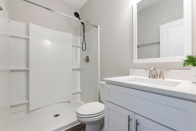 bathroom featuring walk in shower, wood-type flooring, vanity, and toilet