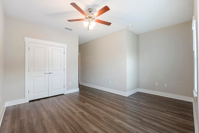 unfurnished bedroom featuring dark wood-type flooring, ceiling fan, and a closet