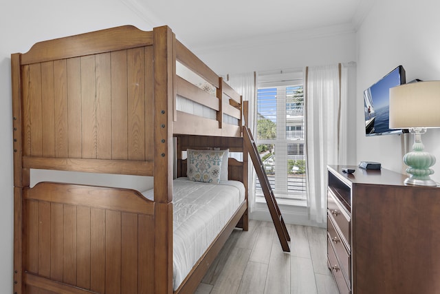 bedroom with light wood-type flooring and crown molding