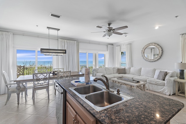 kitchen with light tile patterned floors, pendant lighting, sink, dishwasher, and a water view