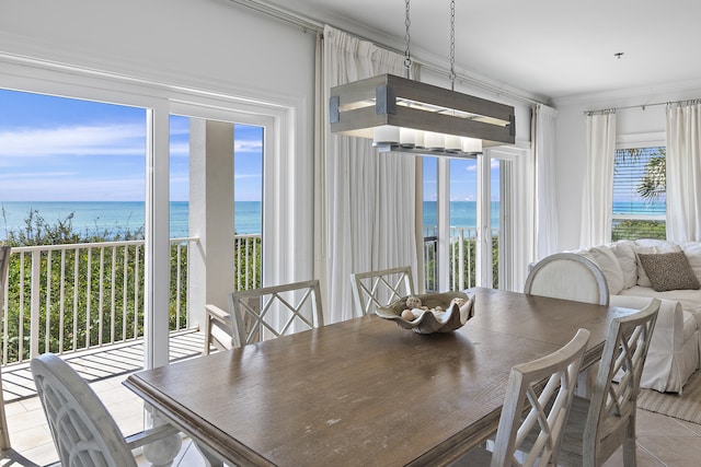 dining space featuring a water view, a beach view, a healthy amount of sunlight, and crown molding